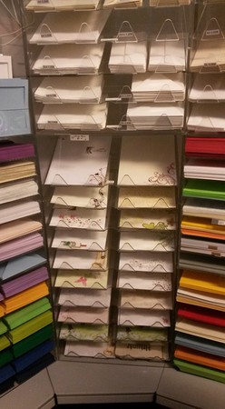 Verschiedene Briefumschläge und farbiges Papier in einem Regal im Schreibwarengeschäft.