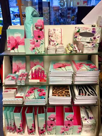 Regal mit Notizbüchern, Mappen und Schreibwaren im floralen Design für Bürobedarf.