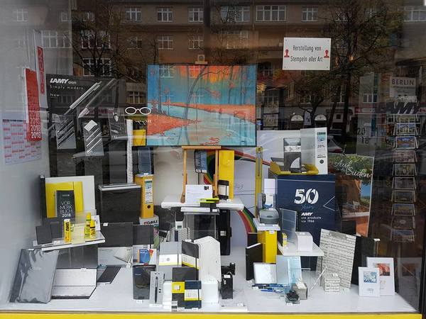 Schaufenster mit Kalendern, Notizbüchern, Schreibwaren und buntem Gemälde dekoriert.